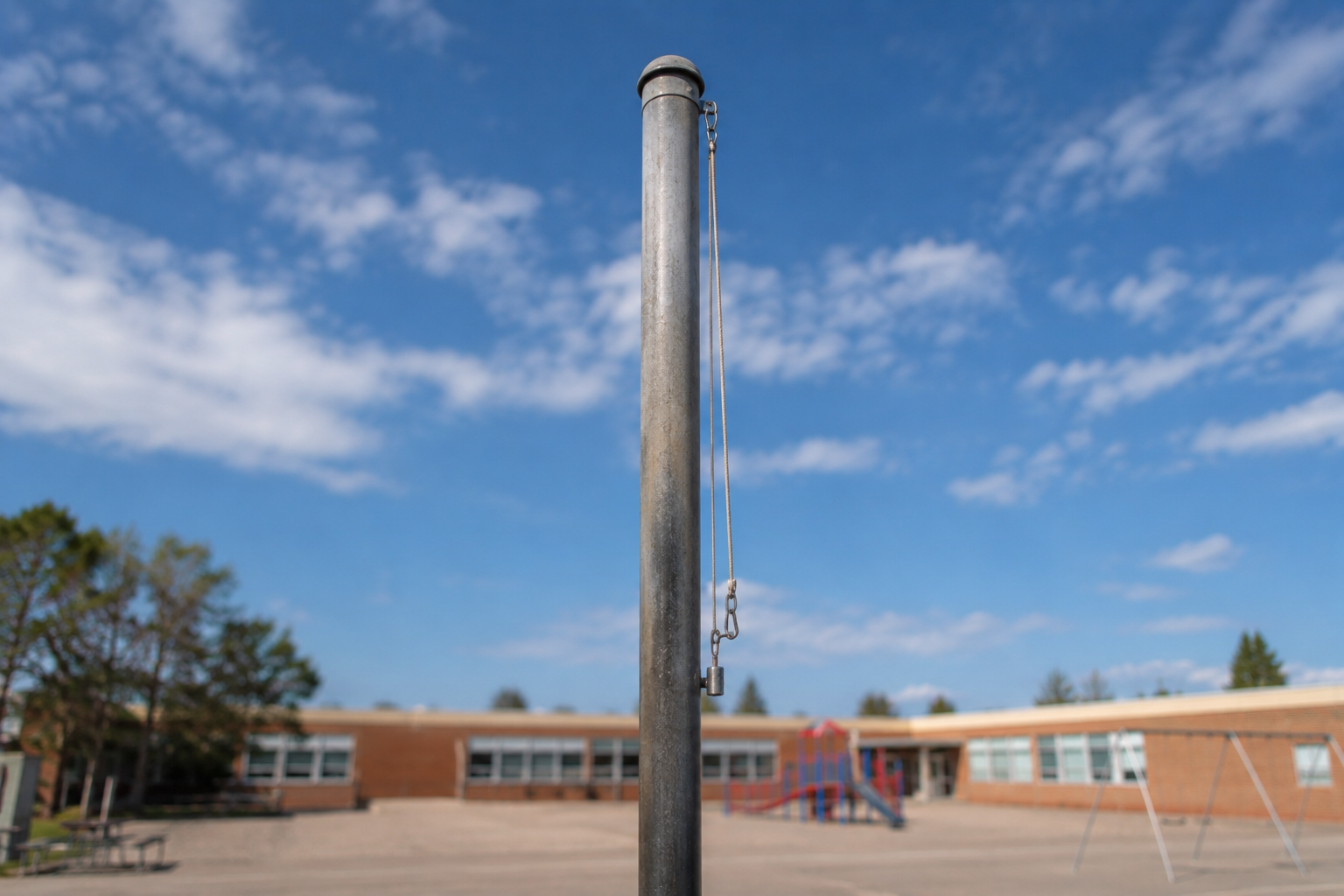 An empty schoolyard flagpole with no flag attached